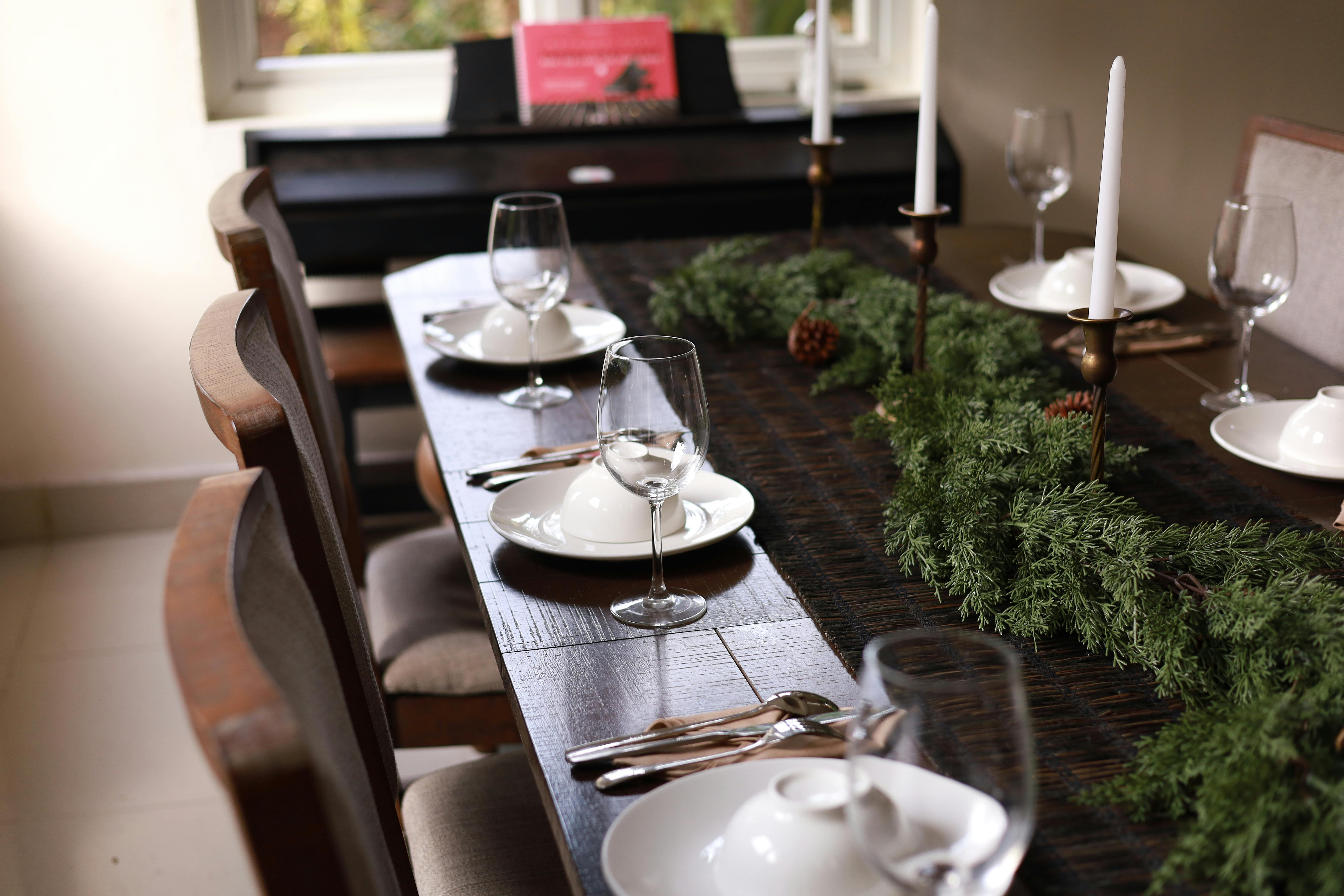 Elegant table setting with Christmas greenery in a cozy dining room.