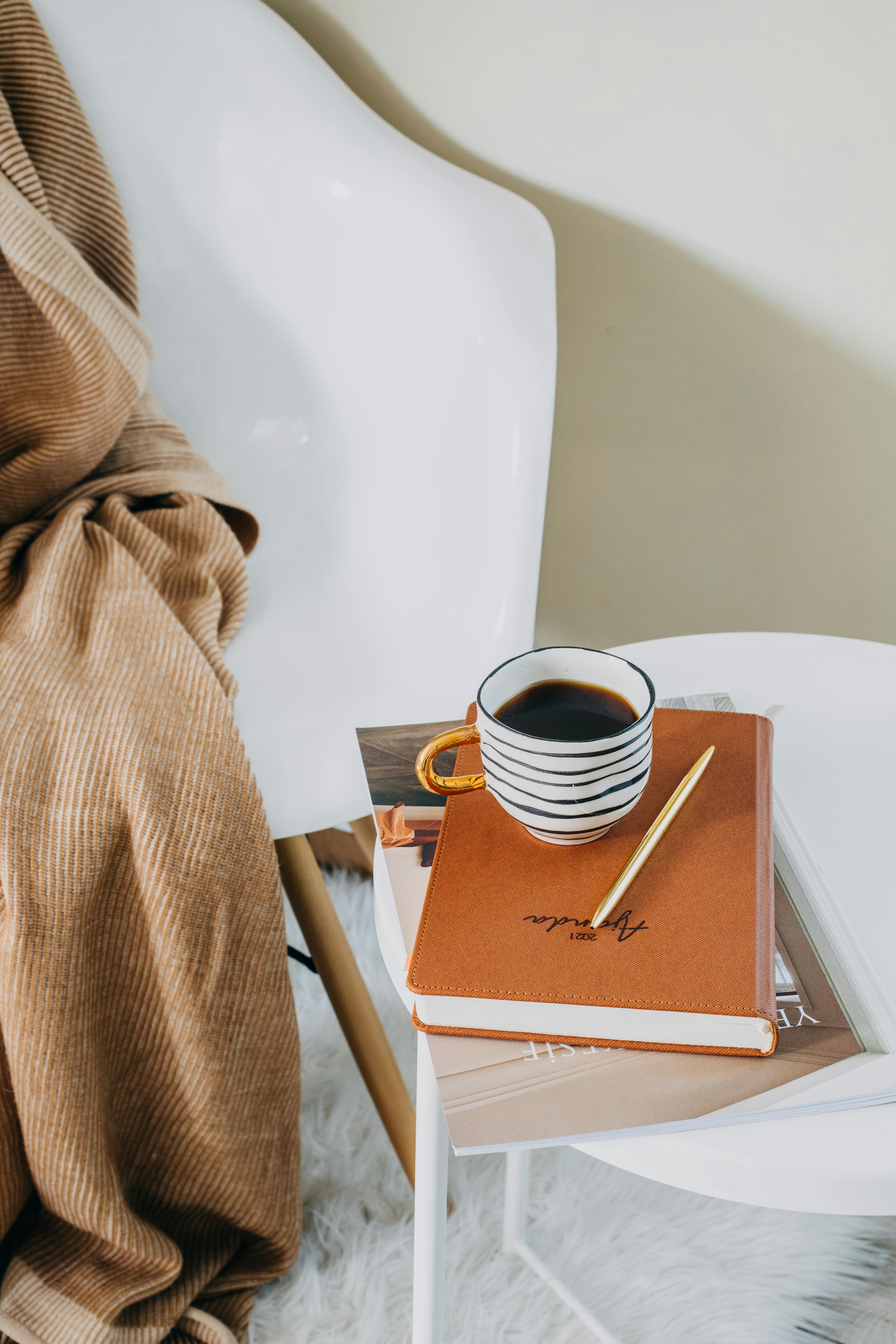 A cozy setup featuring coffee and a journal on a modern chair, ideal for a relaxed morning.