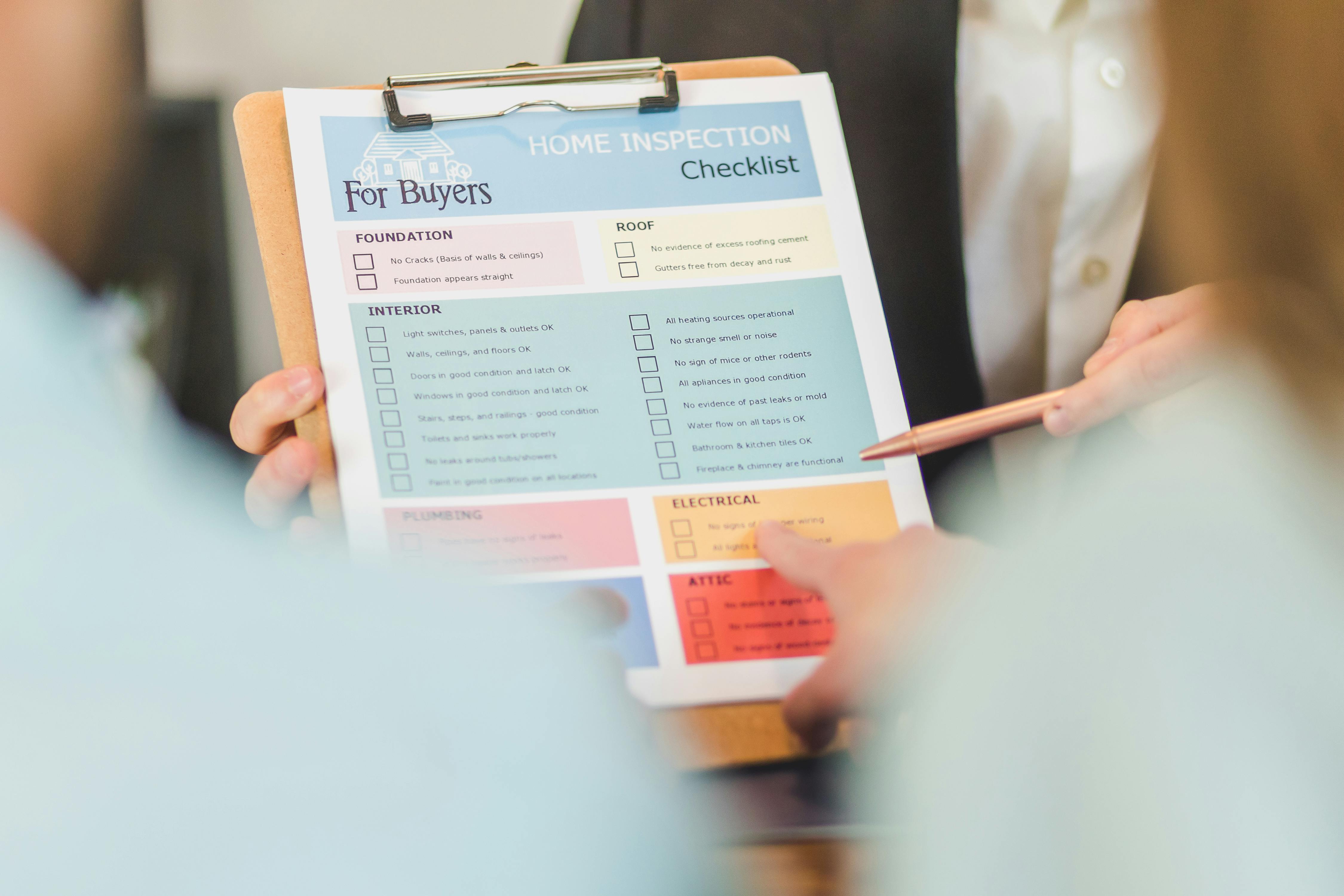 Close-up of hands holding a home inspection checklist clipboard for buyers.